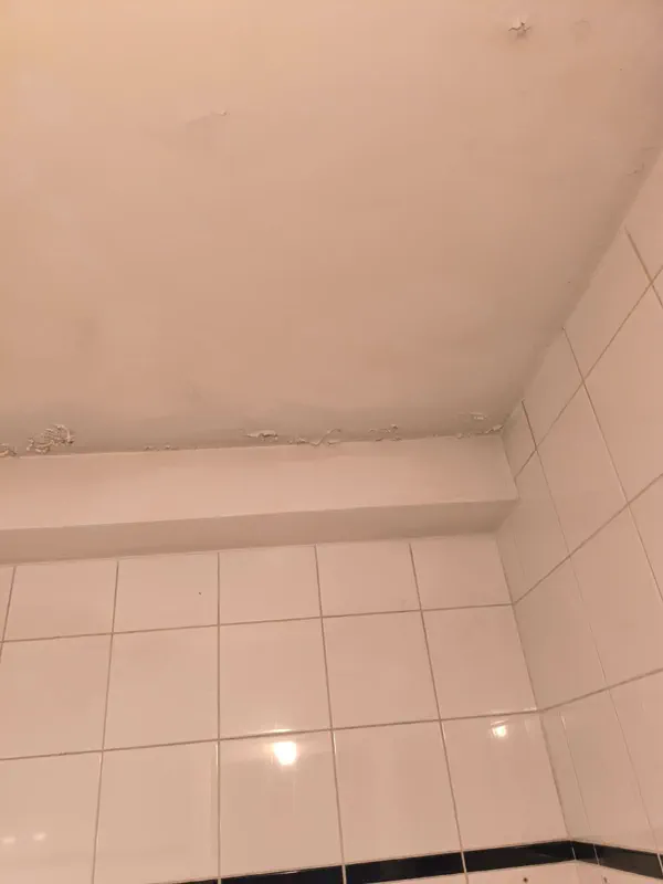 Le même angle de salle de bain assaini, mur et joints remis au propre