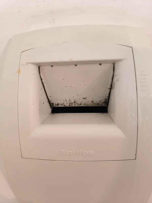 Bouche de VMC noircie par les moisissures avant nettoyage